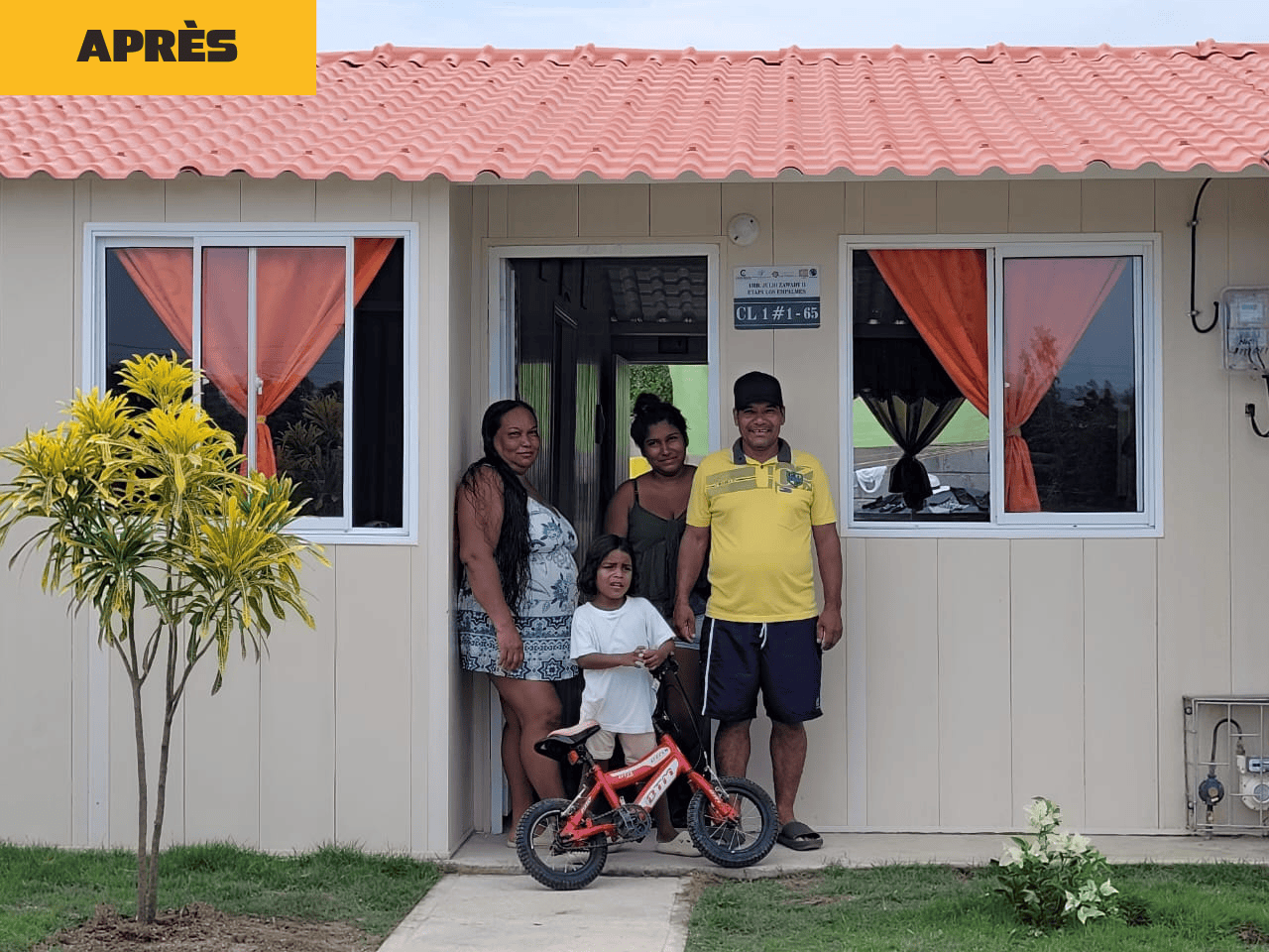 Famille souriante devant sa nouvelle maison rénovée grâce à la prime Fairtrade des bananes équitables.